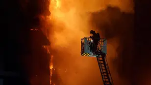 Un bombero trata de apagar el edificio en llamas, en el barrio de Campanar, a 22 de febrero de 2024, en Valencia,