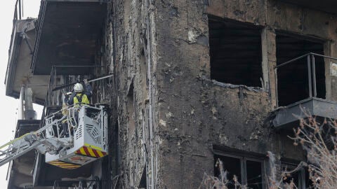 Unos bomberos trabajan en el saneamiento de la fachada del edificio siniestrado en el barrio valenciano de Campanar. 