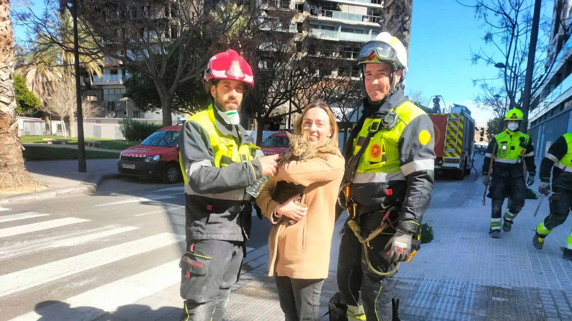 Bomberos de València entregan el gato a su dueña, rescatado de entre los escombros del incendio de Campanar.