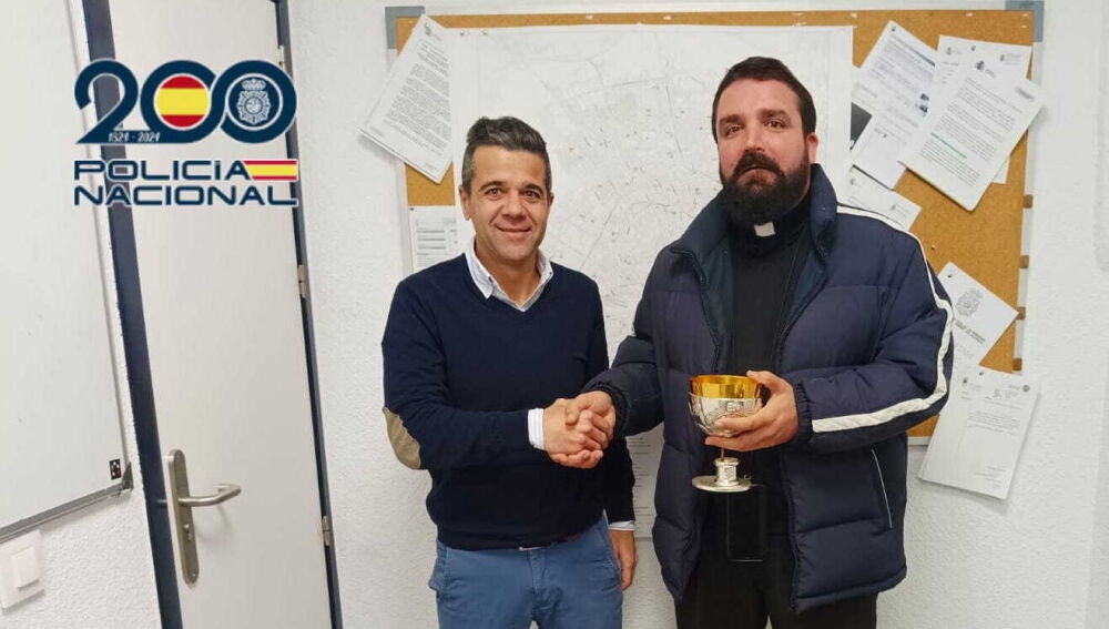 Un agente entrega el caliz robado al sacerdote de la iglesia asaltada