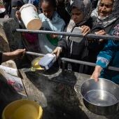 Palestinos desplazados internos sostienen cuencos vacíos mientras hacen fila para recibir ayuda alimentaria en el campo de refugiados de Rafah, en el sur de la Franja de Gaza, el 7 de marzo de 2024.