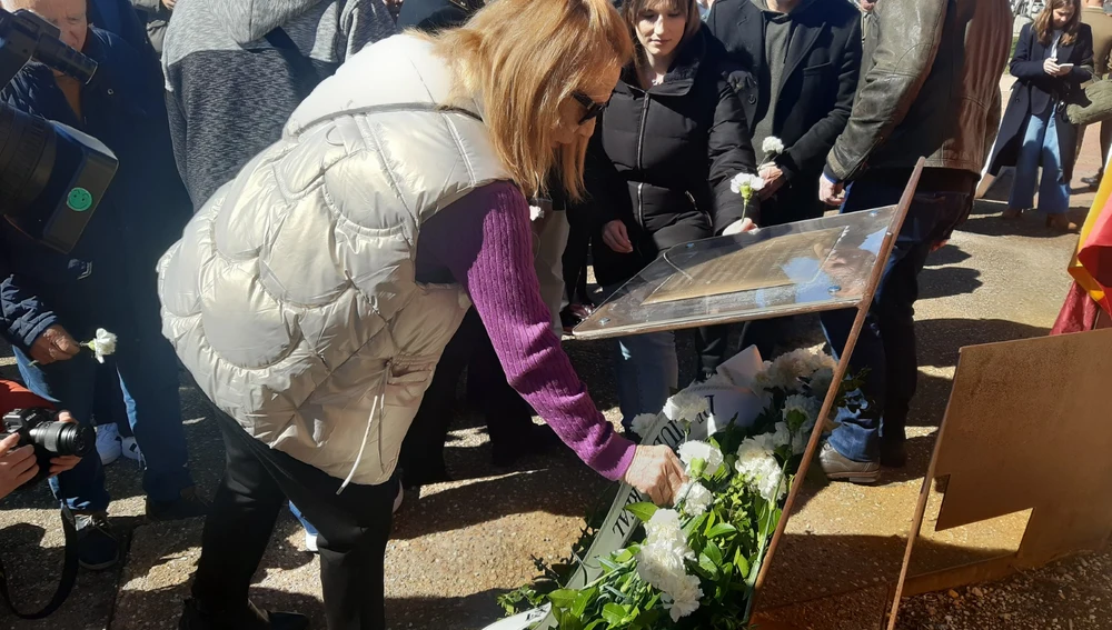Una persona deposita un clavel blanco en el monumento del Parque de Atocha