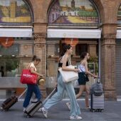 Turistas con equipaje caminan por el centro de la ciudad en foto de archivo