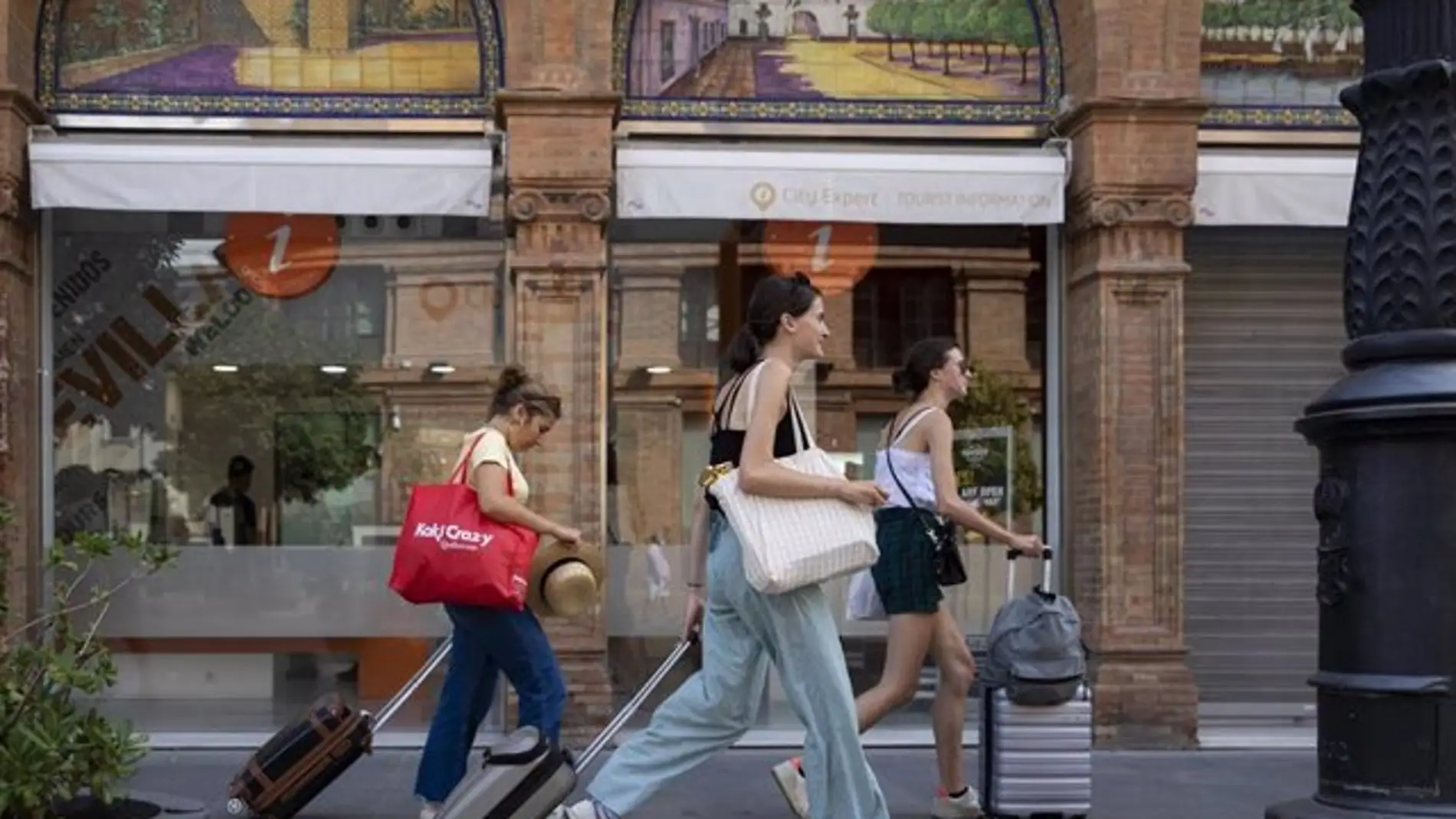 Turistas con equipaje caminan por el centro de la ciudad en foto de archivo