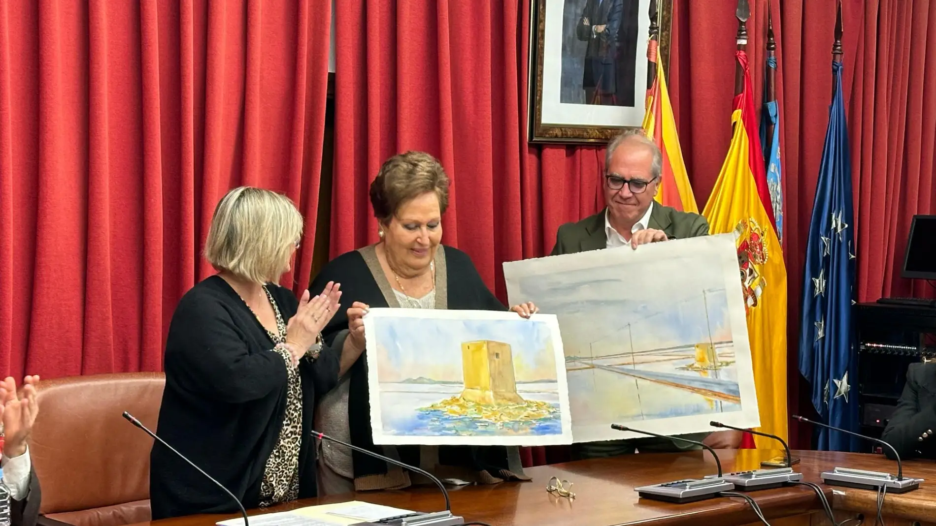 La alcaldesa de Santa Pola entrega a la viuda de Miguel Cuervo-Arango las dos láminas del artista Juan Ródenas Cerdá sobre las Salinas.