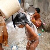 Una mujer baña a su hija en la colonia Wari Sweeper de Dacca, Bangladesh
