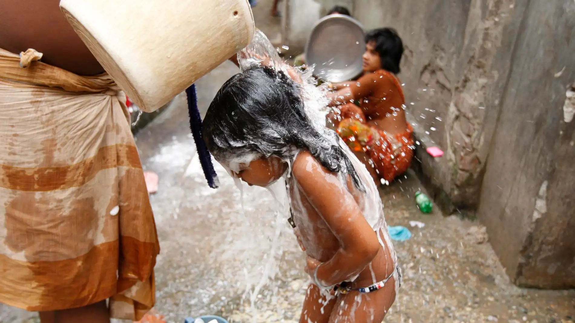Una mujer baña a su hija en la colonia Wari Sweeper de Dacca, Bangladesh