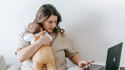 Una mujer con su bebé recién nacido teletrabaja desde su casa