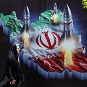 Una mujer iraní pasa junto a una pancarta antiisraelí con imágenes de misiles iraníes, en Teherán