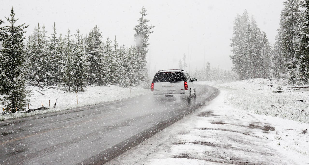 Imagen de archivo de un coche circulando por una carretera llena de nieve Imagen de archivo de un coche circulando por una carretera llena de nieve