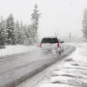 Imagen de archivo de un coche circulando por una carretera llena de nieve