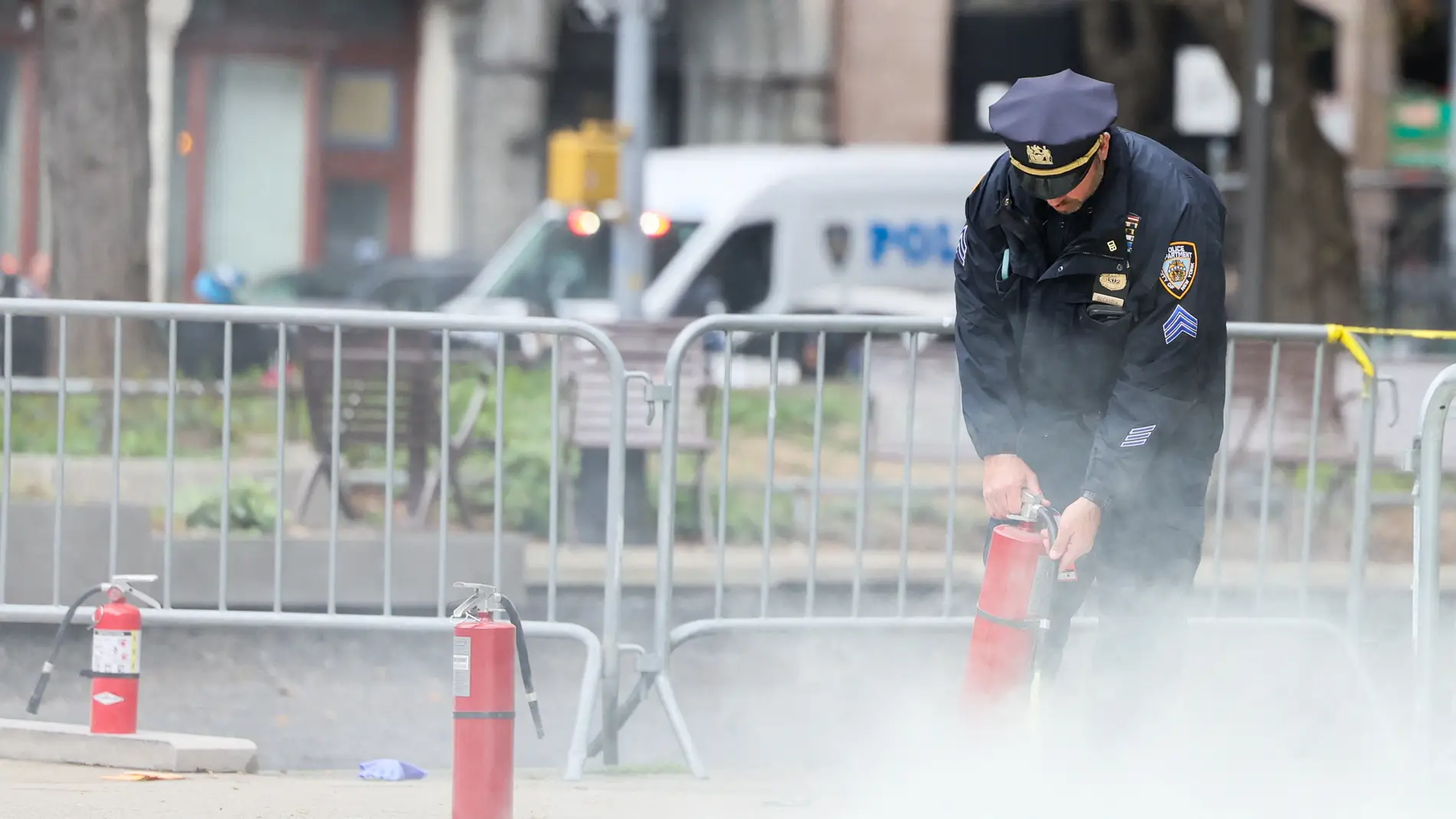 Un agente usa un extintor en el lugar donde un hombre se quemó a lo 'bonzo' a las afueras del tribunal donde juzgan a Trump.