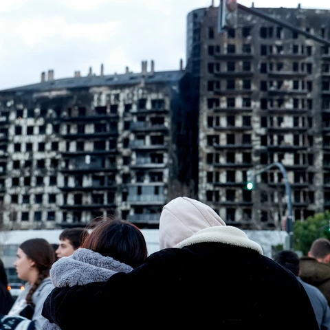 Una pareja observa abrazada el edificio incendiado en el barrio de Campanar de València. 