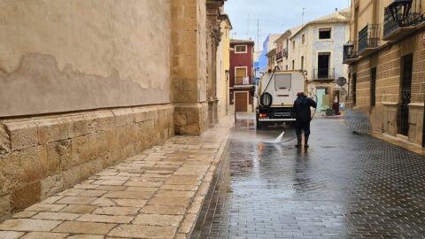 Un trabajador del servicio de limpieza baldea una calle en Aspe. 