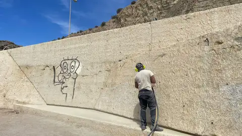 Un operario trabaja para borrar una pintada Un operario trabaja para borrar una pintada