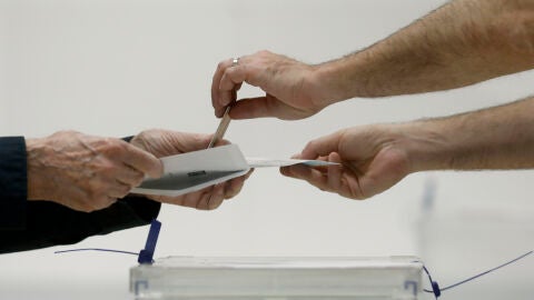 Imagen de archivo de una urna y una persona votando