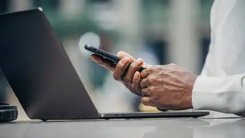 Imagen de archivo de una persona mayor con un teléfono móvil y un ordenador El Banco de España avisa de la estafa de las "cuentas mula": utilizan tus datos para blanquear dinero