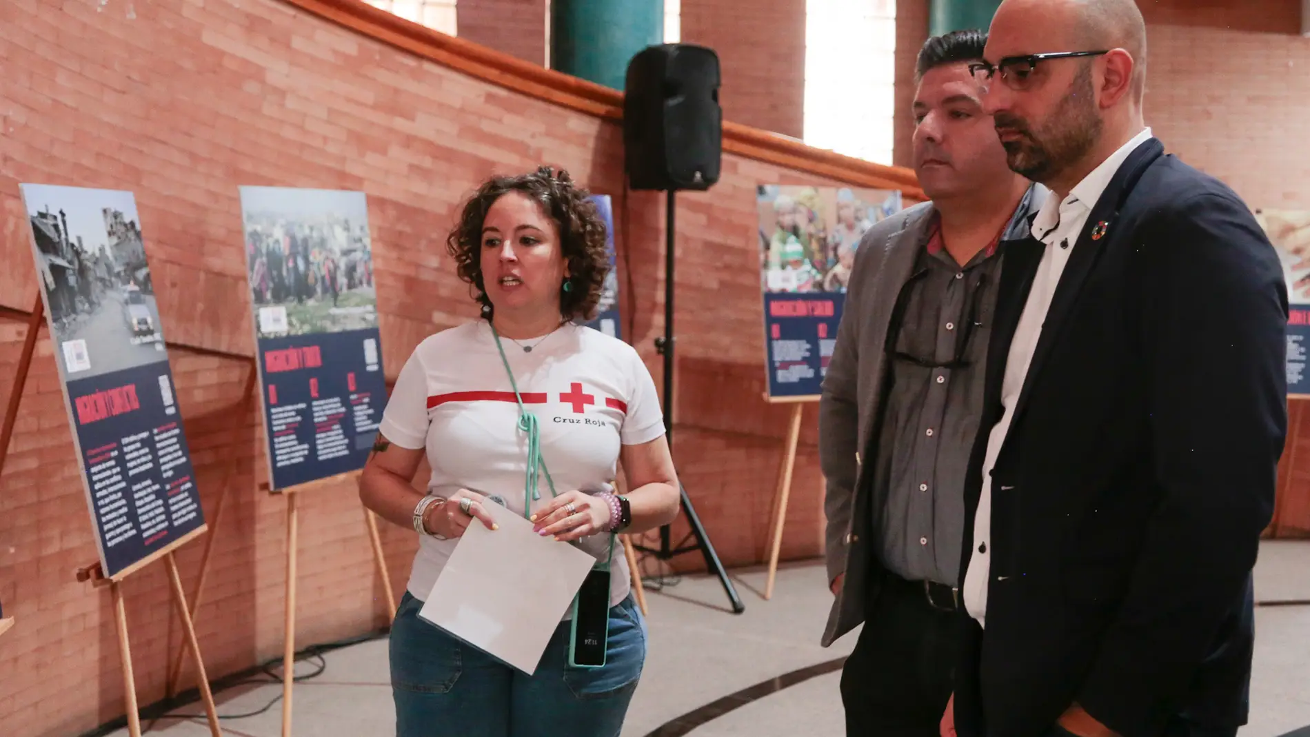 Voluntaria de Cruz Roja junto al presidente de la entidad en Extremadura, Jesús Palo, y el concejal de Cooperación, Ángel Calle, visitan las exposición