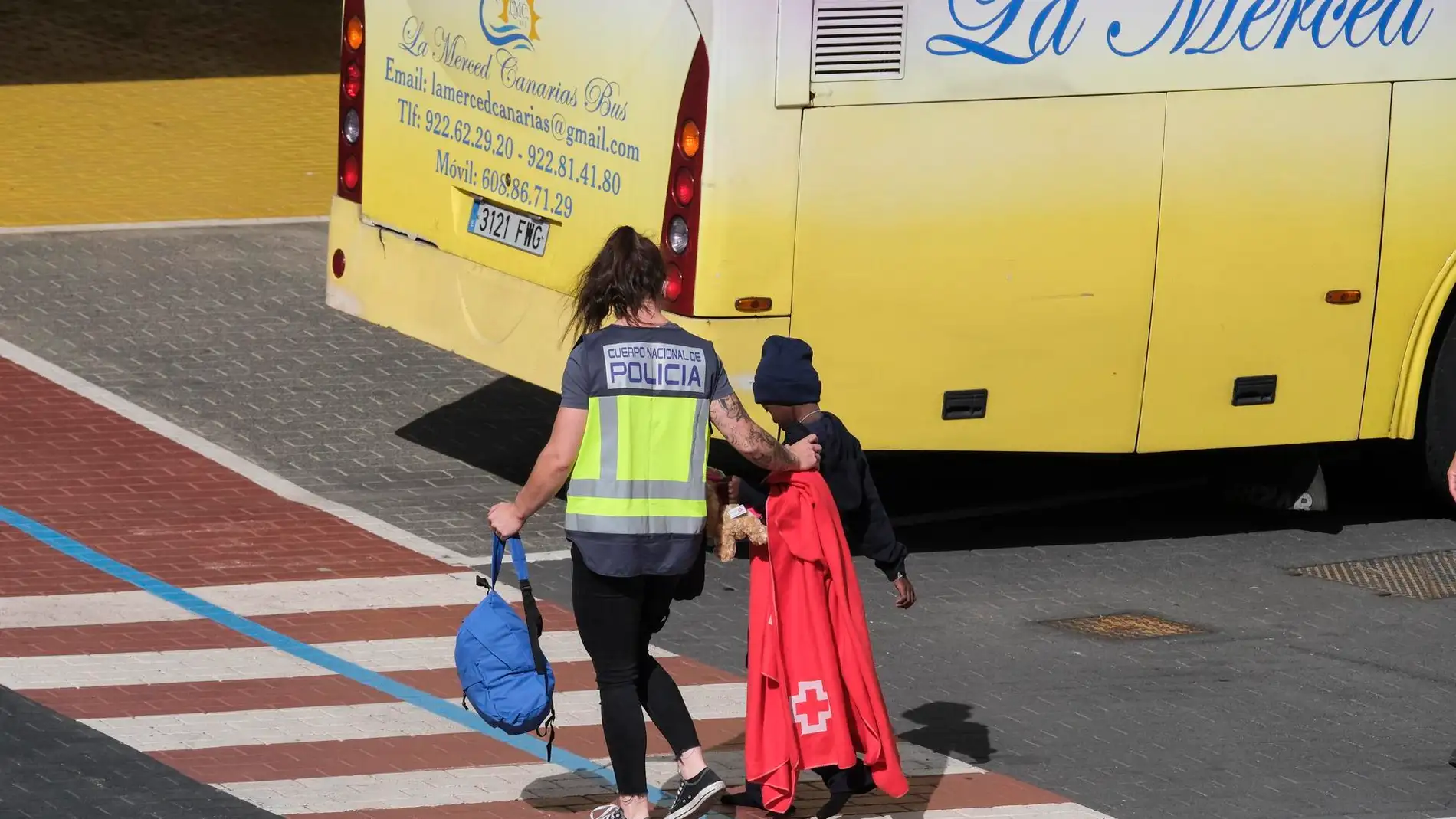 Una agente de la Policía Nacional acompaña a uno de los menores trasladados hasta Santa Cruz de Tenerife el pasado 21 de junio tras ser rescatado en un cayuco