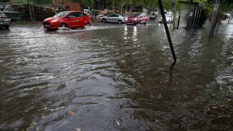 Varios vehículos circulan por una calle inundada. Varios vehículos circulan por una calle inundada.