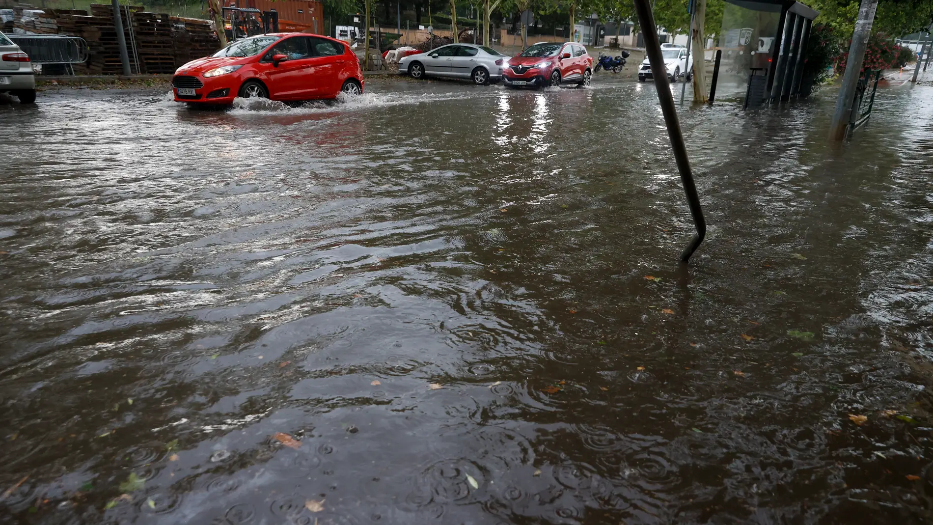 Varios vehículos circulan por una calle inundada. 