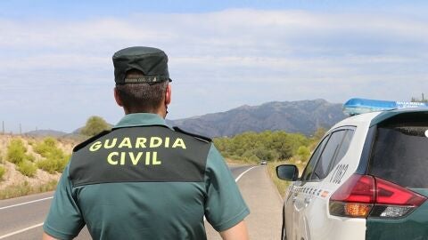 Imagen de archivo de un agente de la Guardia Civil junto a un veh&iacute;culo en una carretera.