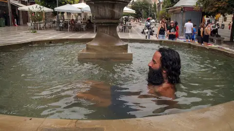 Un hombre se refresca en una fuente de Plaza Nueva, este jueves en Granada. Comienza una semana que será más cálida de lo normal tras la pequeña 'tregua' de temperaturas