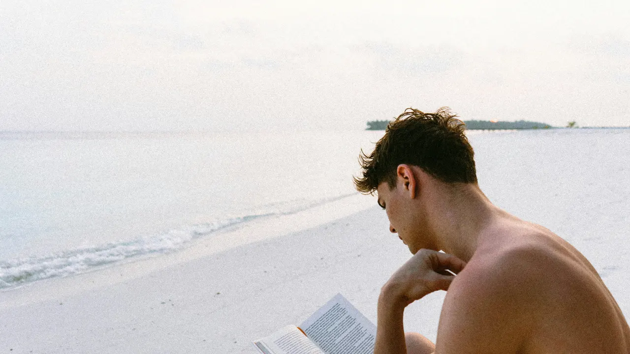Joven leyendo en la playa