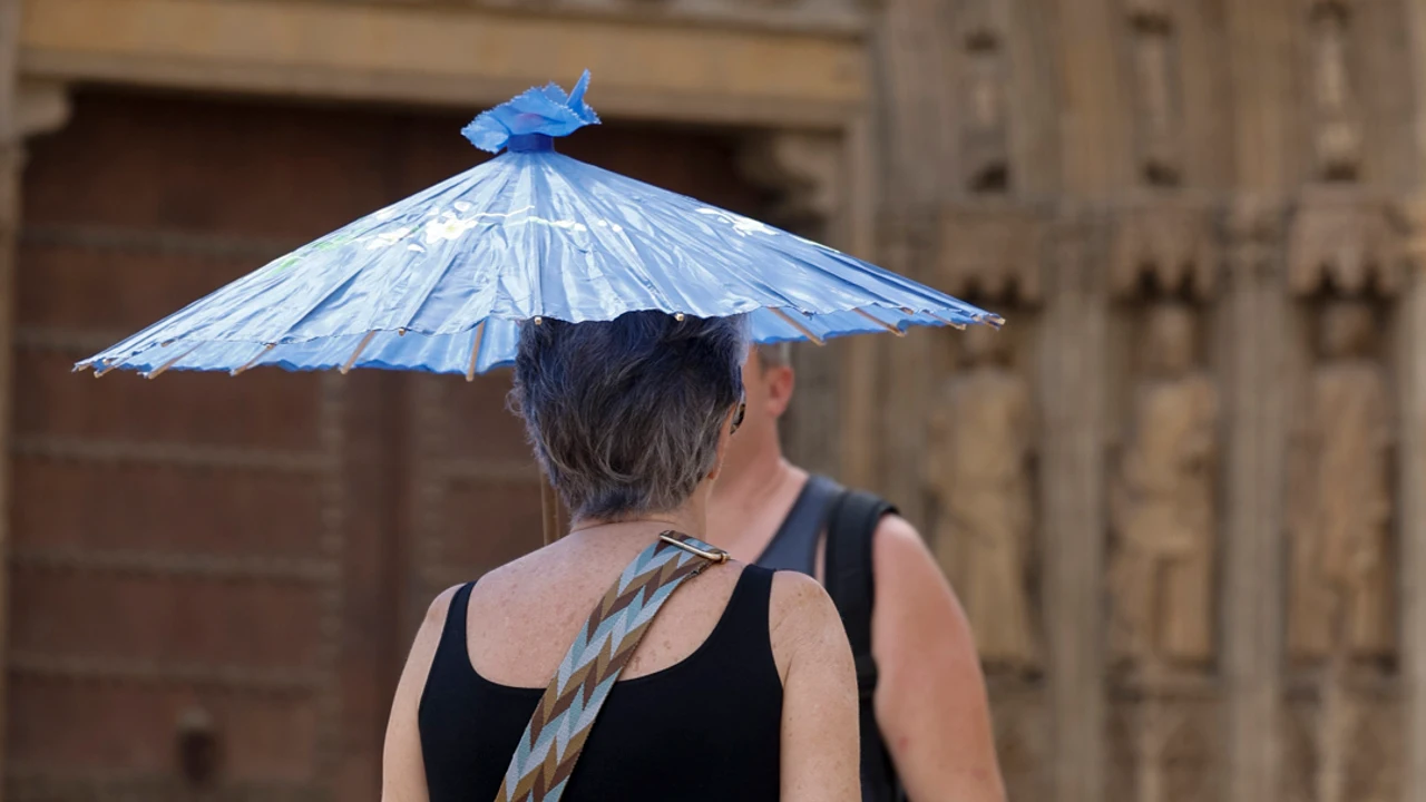 Una persona se protege del calor con una sombrilla mientras pasea por el centro de Valencia.
