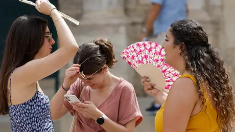 Tres personas se protegen del calor Tres personas se protegen del calor