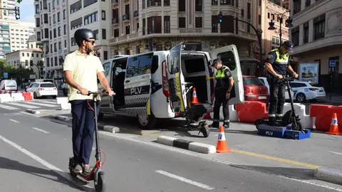 Un policia local realiza un control a un patinete en la ciudad de Valencia Un policia local realiza un control a un patinete en la ciudad de Valencia