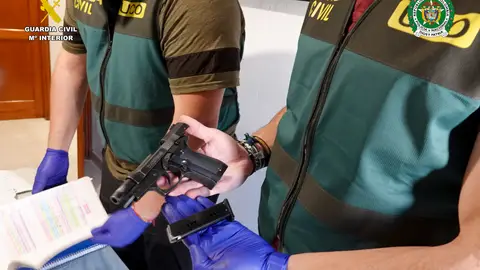 Agentes de la Guardia Civil con una pistola intervenida en la operación. Agentes de la Guardia Civil con una pistola intervenida en la operación.