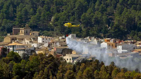 Un helicóptero trabaja refrescando el perímetro de la localidad de Penáguila que se ha visto obligada a desalojar a sus 800 vecinos a causa del incendio forestal declarado a media tarde de este martes. Un helicóptero trabaja refrescando el perímetro de la localidad de Penáguila que se ha visto obligada a desalojar a sus 800 vecinos a causa del incendio forestal declarado a media tarde de este martes.