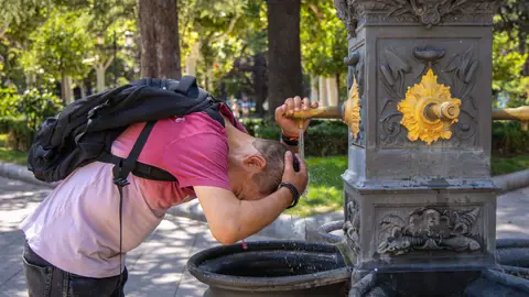 Una persona se refresca con agua de la fuente. Una persona se refresca con agua de la fuente.
