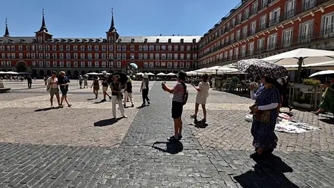 Turistas se protegen del sol con paraguas en la Plaza Mayor de Madrid. Turistas se protegen del sol con paraguas en la Plaza Mayor de Madrid.
