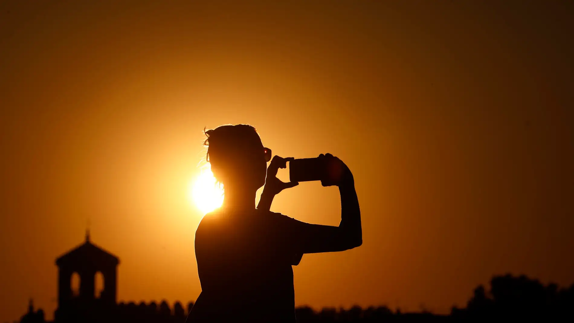 Una persona fotografía el atardecer en una jornada de altas temperaturas. Una persona fotografía el atardecer en una jornada de altas temperaturas.