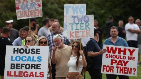 Manifestantes anti-migraci&oacute;n con pancartas durante una protesta en los exteriores del Potters International Hotel, que es la casa de los migrantes en Aldershot, Reino Unido.