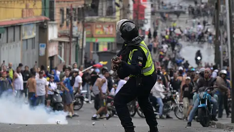 Un oficial de la policía antidisturbios usa gases lacrimógenos contra manifestantes durante una protesta de opositores al gobierno del presidente venezolano Nicolás Maduro. Un oficial de la policía antidisturbios usa gases lacrimógenos contra manifestantes durante una protesta de opositores al gobierno del presidente venezolano Nicolás Maduro.