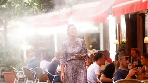 Imagen de archivo. Una mujer pasa por un bar enfriado por vapor de agua durante una ola de calor en Sevilla, España. Imagen de archivo. Una mujer pasa por un bar enfriado por vapor de agua durante una ola de calor en Sevilla, España.