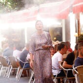 Imagen de archivo. Una mujer pasa por un bar enfriado por vapor de agua durante una ola de calor en Sevilla, España.