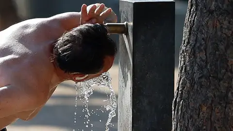 Un hombre bebe en una fuente. Un hombre bebe en una fuente.