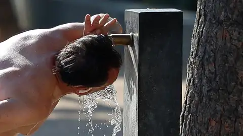 Una persona bebe agua ante el intenso calor Una persona bebe agua ante el intenso calor