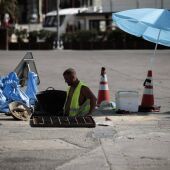 Un trabajador se protege del sol con una sombrilla en Valencia. 