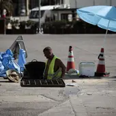 Un trabajador se protege del sol con una sombrilla en Valencia. Un trabajador se protege del sol con una sombrilla en Valencia.