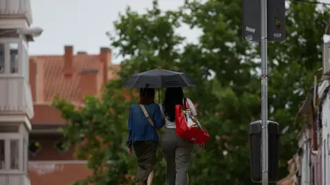 Dos mujeres se protegen de la lluvia con un paraguas en Madrid. Dos mujeres se protegen de la lluvia con un paraguas en Madrid.