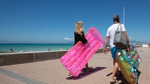 Dos turistas caminan sosteniendo un colch&oacute;n inflable en Palma de Mallorca.