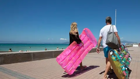 Dos turistas caminan sosteniendo un colchón inflable en Palma Dos turistas caminan sosteniendo un colchón inflable en Palma