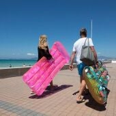 Dos turistas caminan sosteniendo un colchón inflable en Palma 