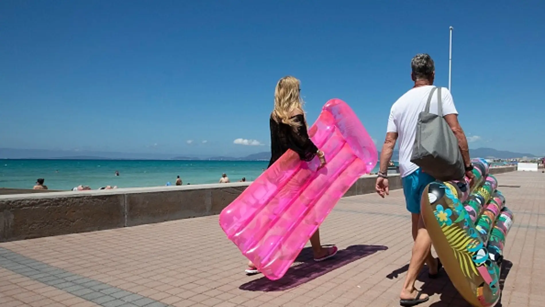 Dos turistas caminan sosteniendo un colchón inflable en Palma de Mallorca. Dos turistas caminan sosteniendo un colchón inflable en Palma de Mallorca.