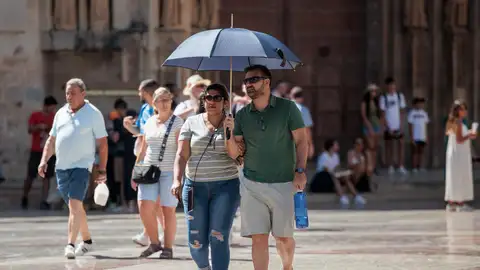 Personas se protegen del calor con una sombrilla en Valencia Personas se protegen del calor con una sombrilla en Valencia